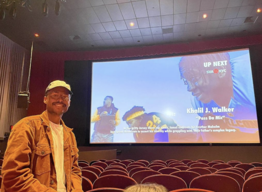 Khalil Walker at the BFA Film thesis screening in the Silas Theater as his film plays in the background.